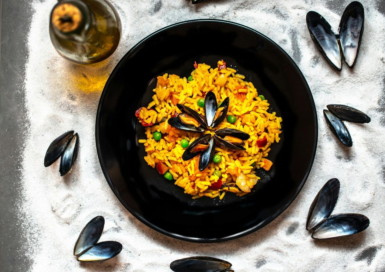 Arroz español. Foto: <a href="https://unsplash.com/@martinb26?utm_source=Hoy%20Apps&utm_medium=referral" target="_blank" rel="noopener">martin becker</a> (<a href="https://unsplash.com/photos/yellow-flowers-on-black-round-plate-Of6BddUs1C8?utm_source=Hoy%20Apps&utm_medium=referral" target="_blank" rel="noopener">Unsplash</a>)